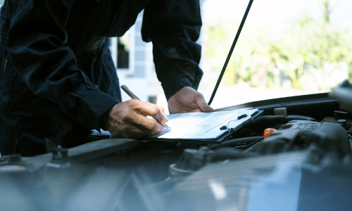 Mechaniker notiert Fahrzeugdaten bei Kfz-Inspektion in der Autowerkstatt Bremen