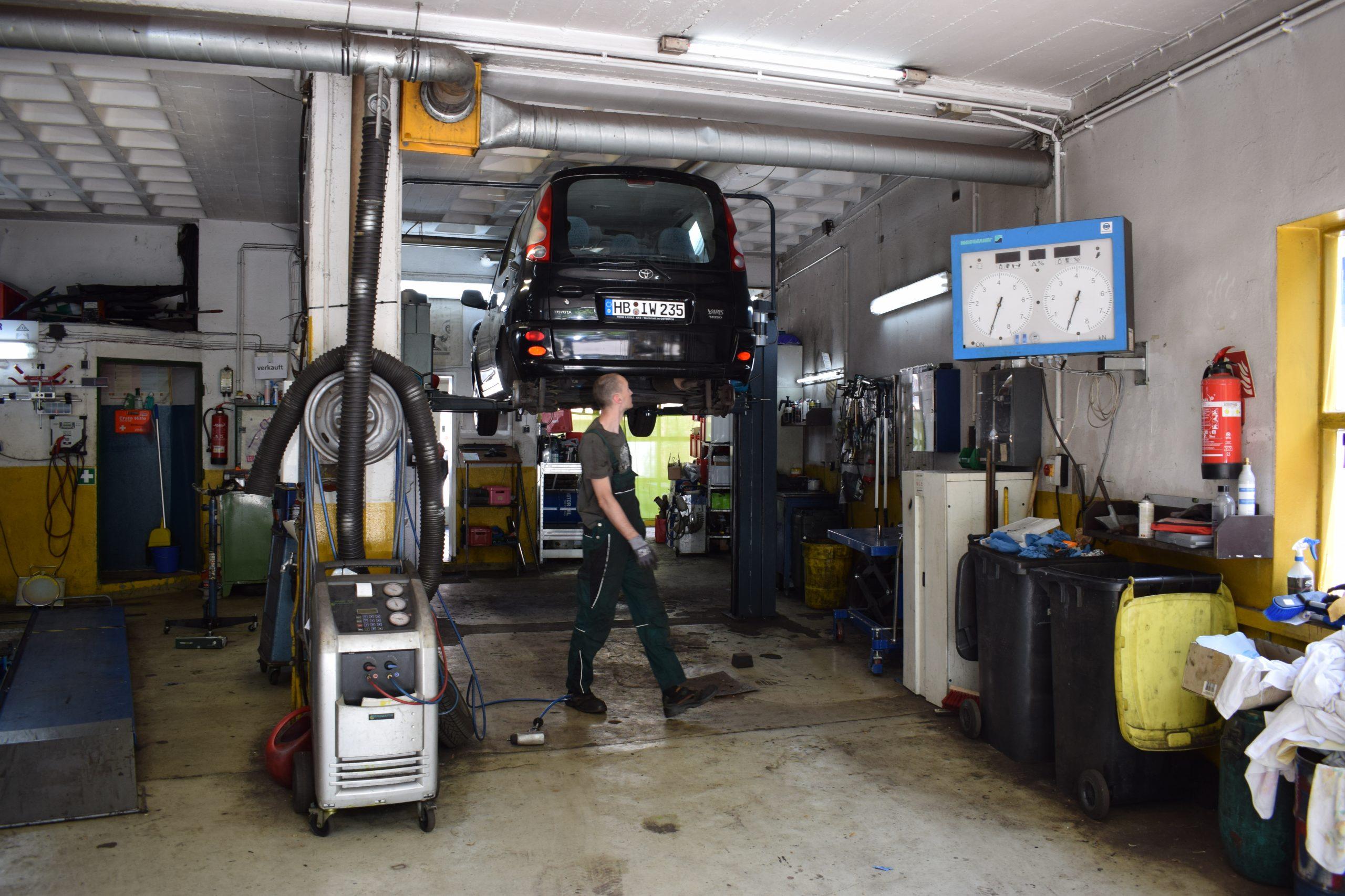 Mechaniker arbeitet an Fahrzeug auf Hebebühne in Autowerkstatt Bremen Ostertor Fahrzeug auf Hebebühne mit Mechaniker in Autowerkstatt Bremen Ostertor