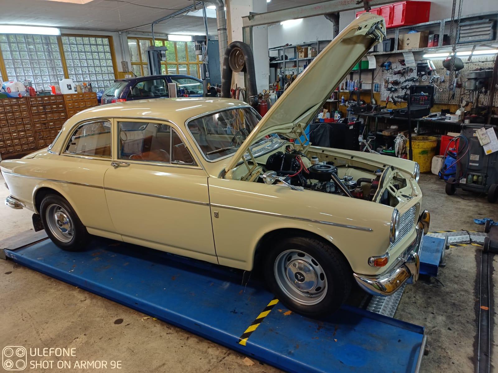 Klassisches Oldtimer-Fahrzeug bei Inspektion in heller Autowerkstatt mit moderner Ausstattung Oldtimer auf Hebebühne mit offener Motorhaube in Autowerkstatt Bremen